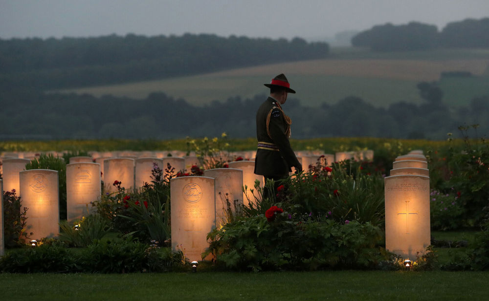 A Canadian serviceman stands among lit up CWGC headstones in a cemetery for the 100th anniversary of the Somme.