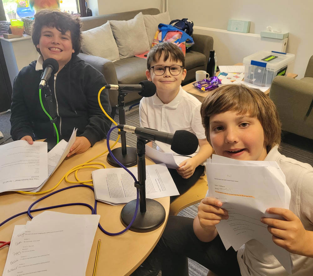 Schoolboys posing for the camera in front of podcast microphones.