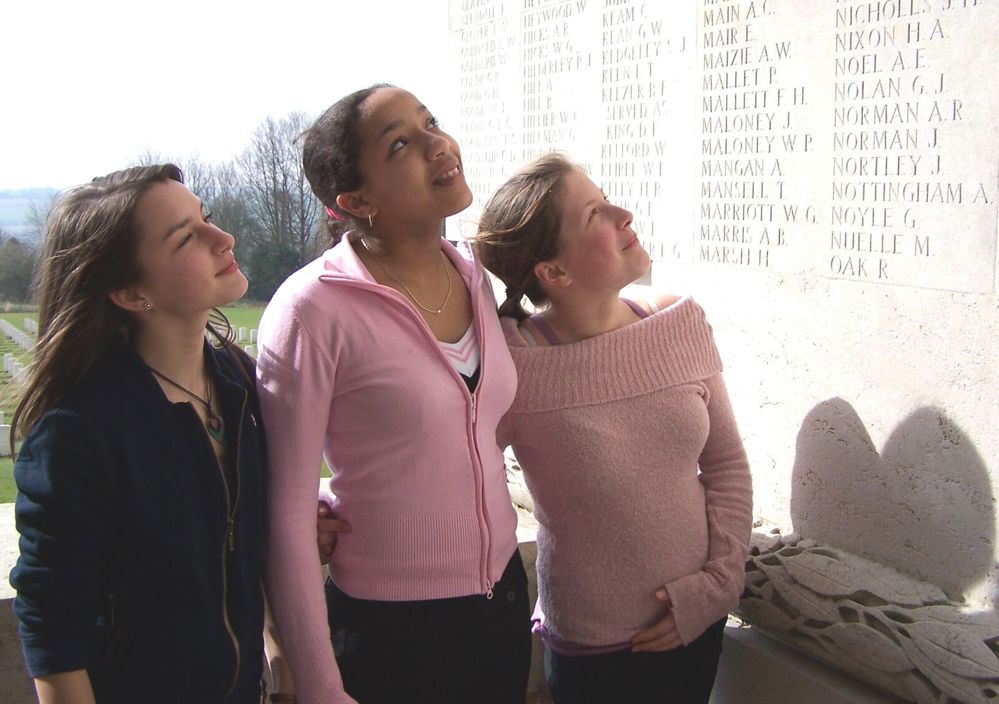 Three young girls looking up at the name panels of the Thiepval Memorial.