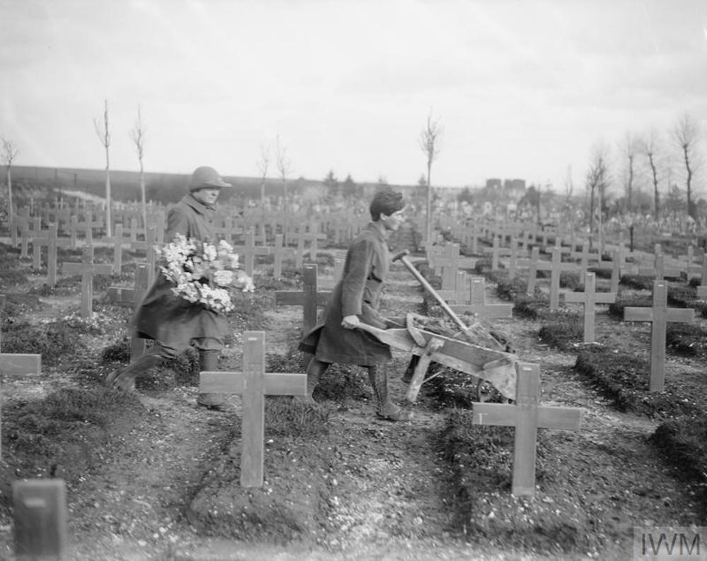 Women tending war graves at Abbeville Military Cemetery in 1918. Graves are marked with simple wooden cross markers.