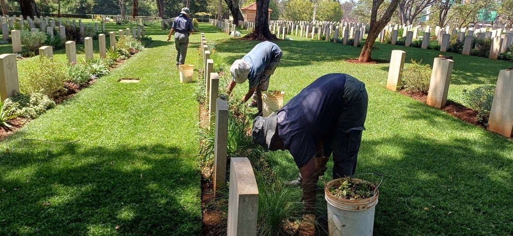 Workers trimming borders at Nairobi War Cemetery.