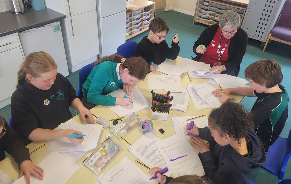School kids hard at work working on paper documents with coloured highlighters.