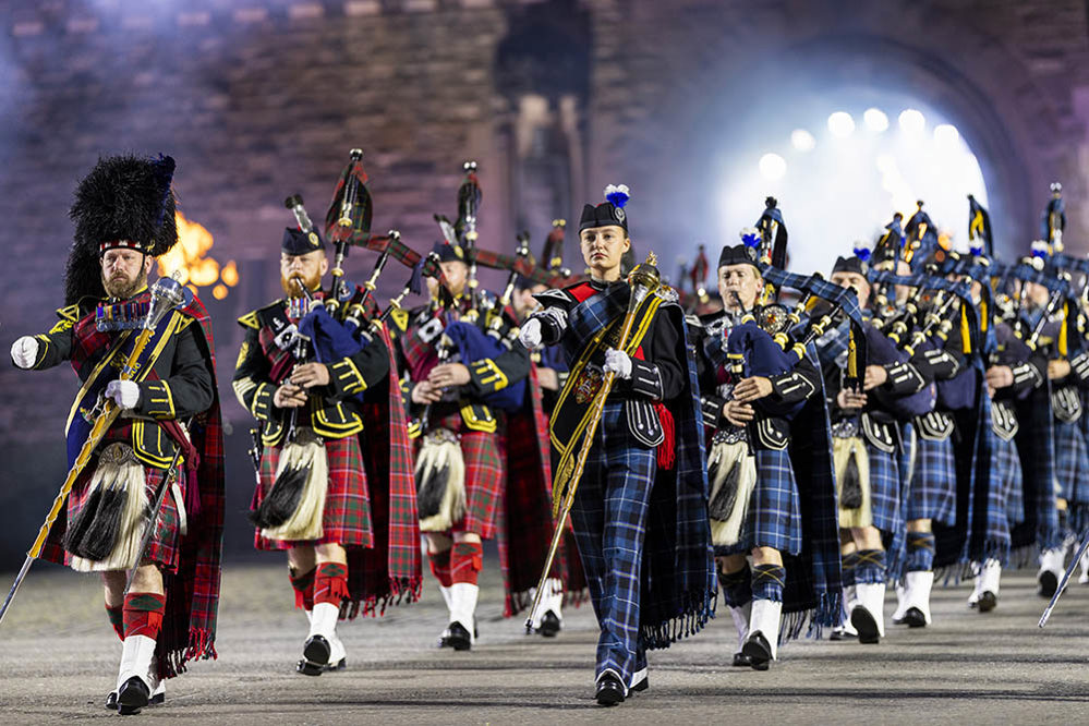 Tartan-clad Scottish Pipes and Drums band marches through a slightly misty gateway into the parade ground at Edinburgh Castle.
