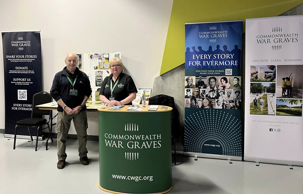 A CWGC pop-up stand complete with banners. Two staff members are manning the pop-up kiosk.
