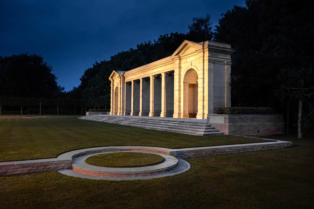The Bayex Mmorial at night illuminated by lights under a pleasing navy blue night sky.